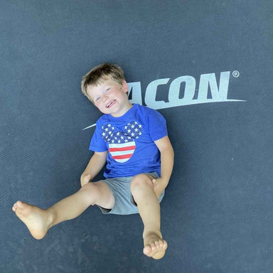 A happy boy lying on an Acon trampoline.